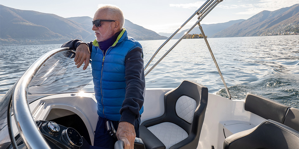 A man driving a boat with a bubble vest in the colder weather